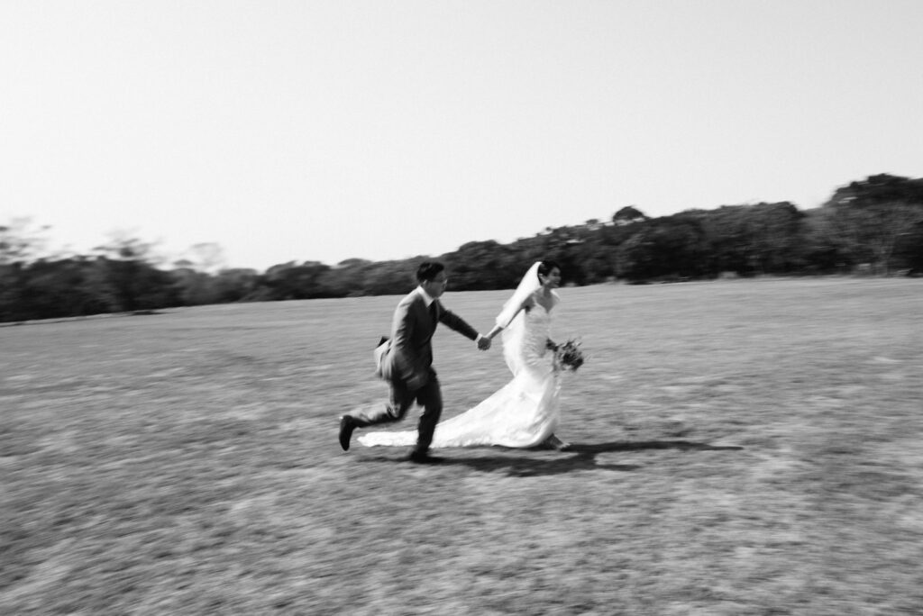 新人牽手奔跑於戶外草地上，動態捕捉婚禮的真摯情感